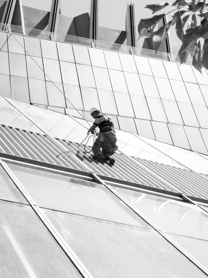 A window cleaner working on a modern architectural facade in black and white.