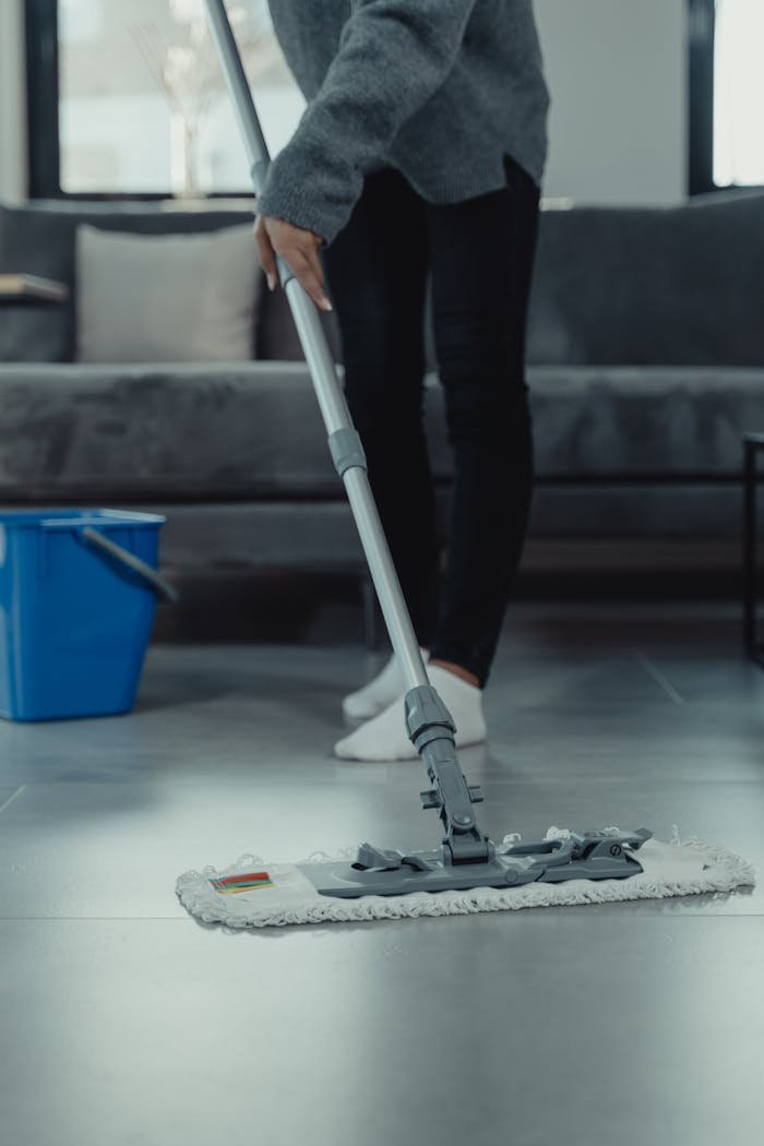 Close-up of person mopping a clean tile floor in a contemporary living room.
